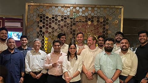 13 alumni standing with Ben Cole in New Delhi at The Imperial Spice restaurant. They are standing together and smiling.